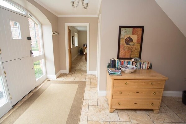 A hallway with a wooden dresser, a rug, and a painting on the wall.