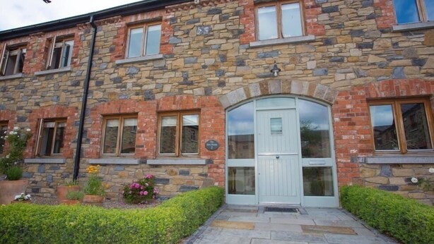 A stone building with a white door and multiple windows. - The Hen House 10065 (Lismullin)