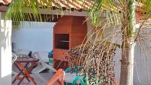 Un pequeño espacio al aire libre con una palmera, un muro de ladrillo y sillas de plástico.