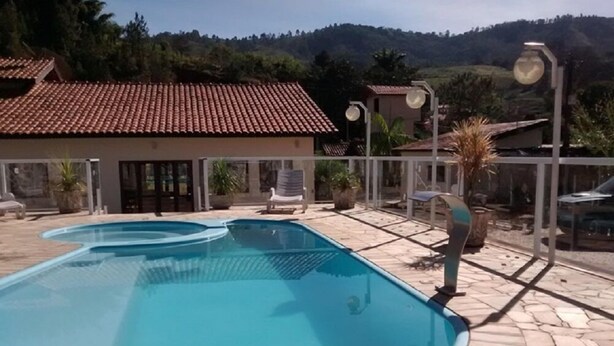 Una piscina rectangular con solárium empinado, rodeada de sillas de descanso y plantas en macetas.