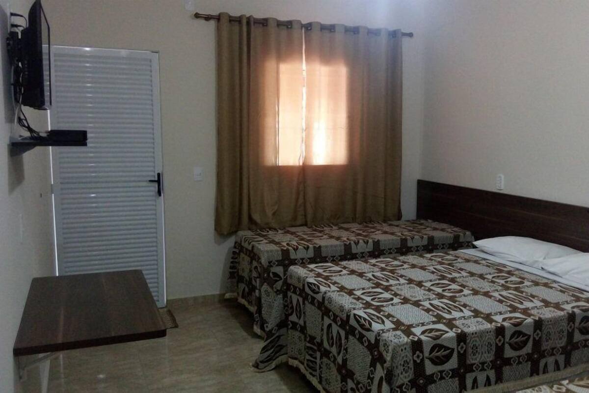 A bedroom with two beds, a wardrobe, and a window with curtains.