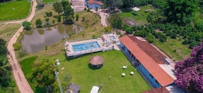 Vista aérea de una propiedad con piscina, cancha de tenis y un amplio césped.
