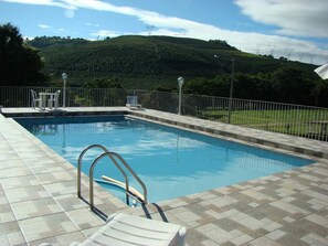 A swimming pool with a view of hills and power lines in the background. - Pousada Primavera da Serra (Serra Negra)