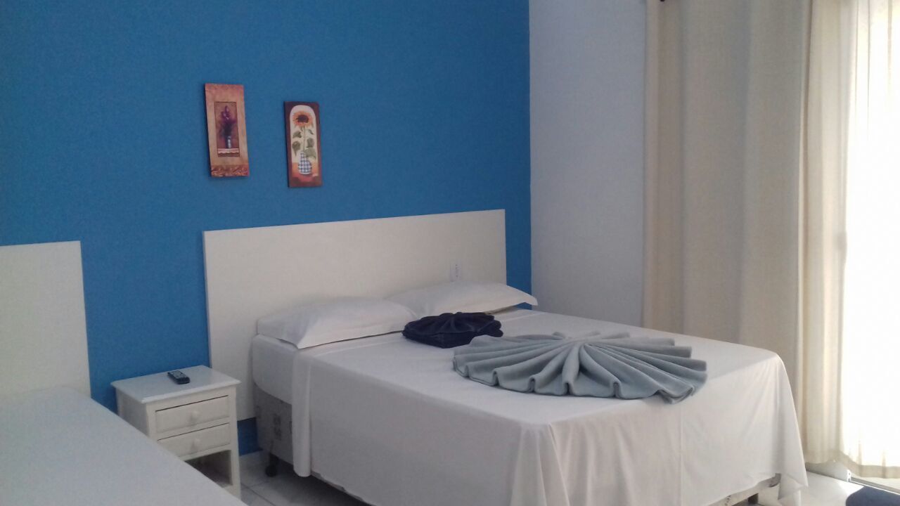 A hotel room with a single bed, a nightstand, and a blue accent wall.
