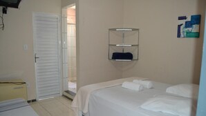A hotel room with a bed, a small desk, and a storage unit on the wall. - Pousada Sitio Bom Fim (Serra Negra)