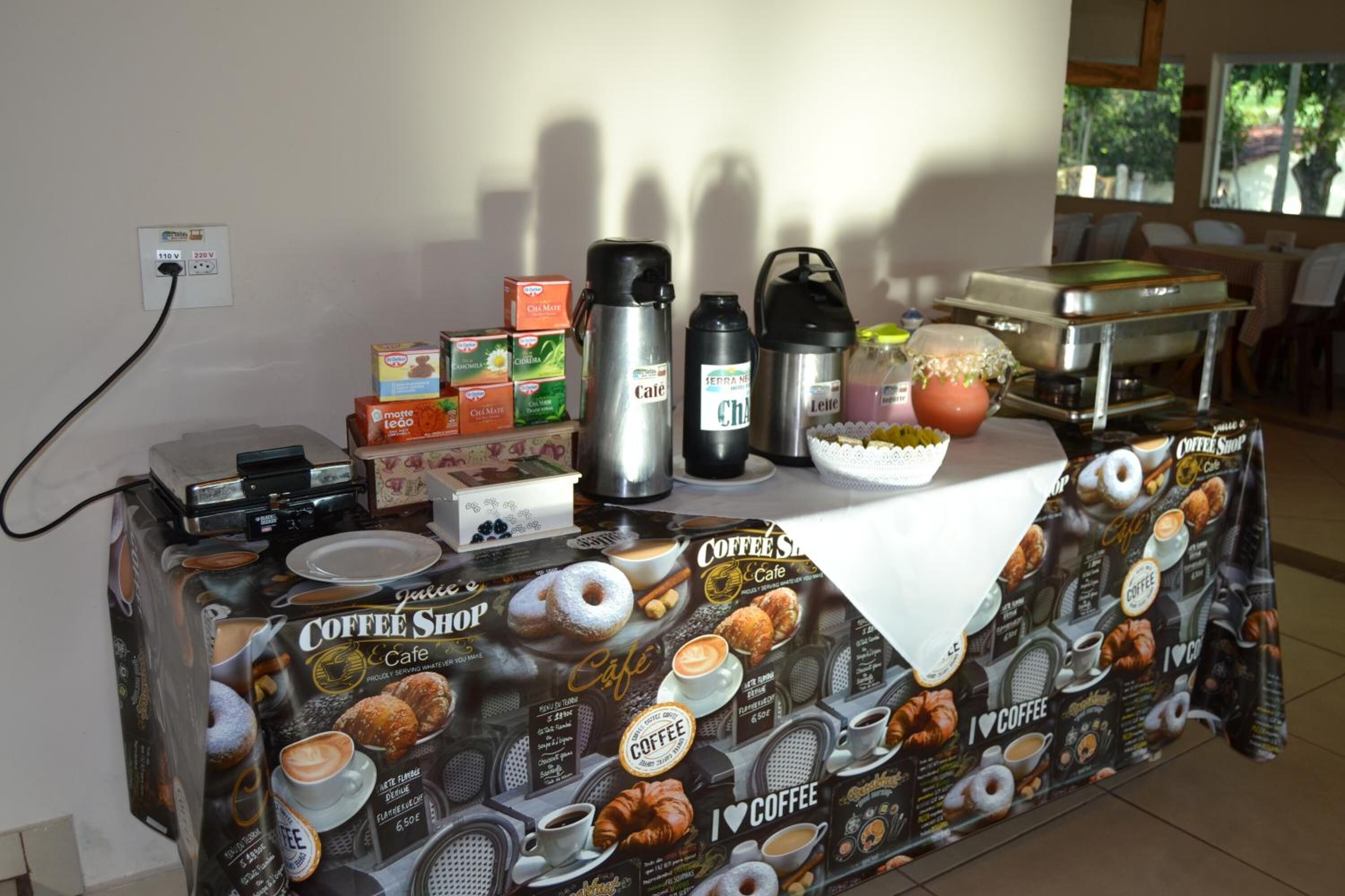 A coffee shop setup with a coffee machine, thermos, and various coffee containers on a table.