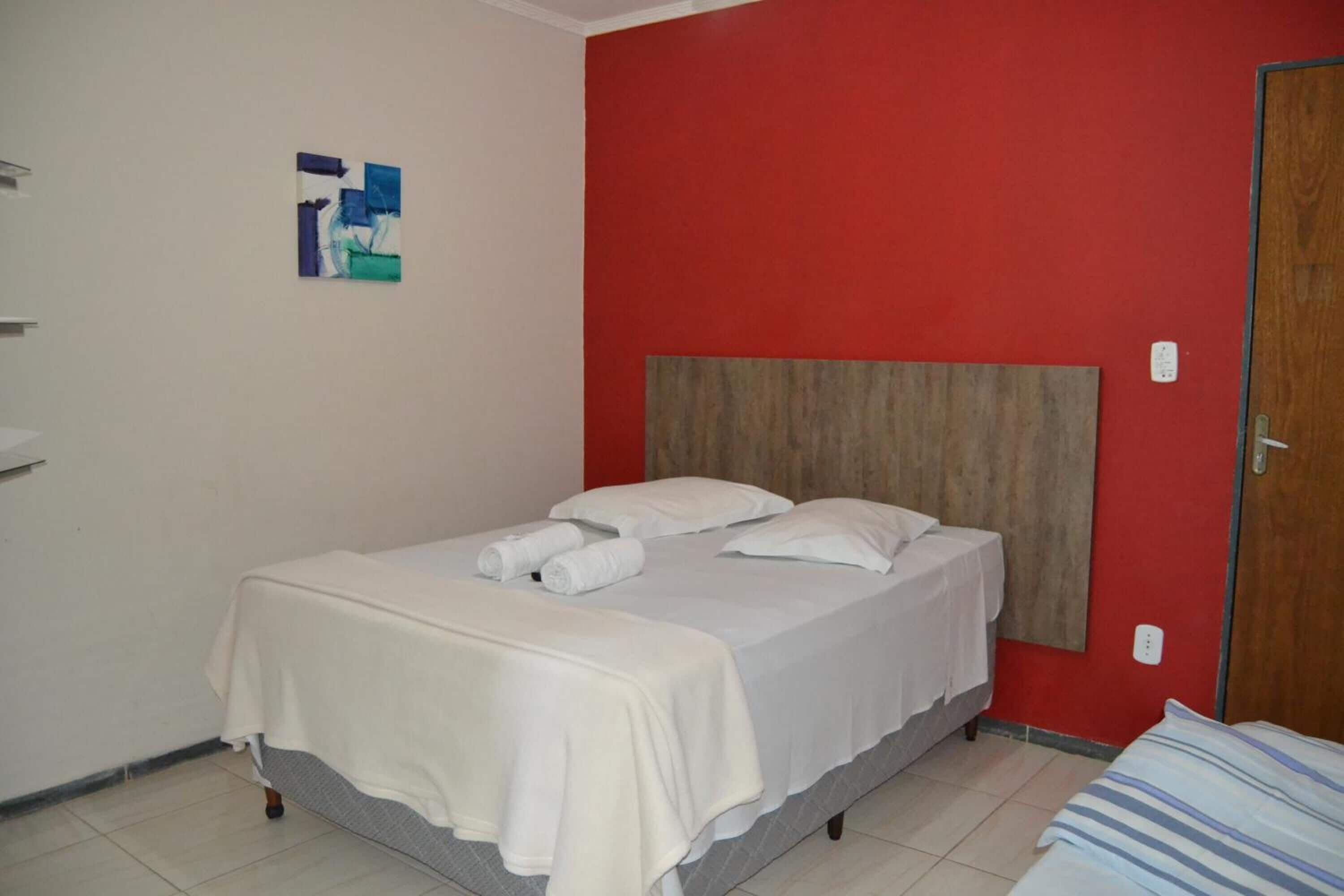 A single bed with a wooden headboard, white bedding, and a small artwork on the wall.