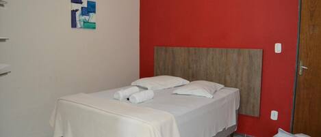 A single bed with a wooden headboard, white bedding, and a small artwork on the wall.