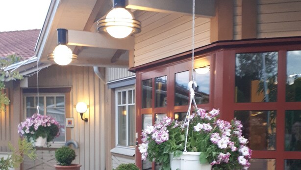 En bygning med rød facade, store vinduer og blomsterkasser.