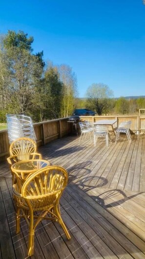 A wooden deck with outdoor furniture, including wicker chairs and a table. - Hotell Indalsleden (Bispgården)