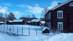 A snow-covered wooden building with a fenced yard, likely a historic site or museum. - Hotell Indalsleden (Bispgården)