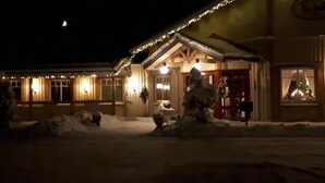 En bygning med sneklædt indgang, træfacade og lyskæder.