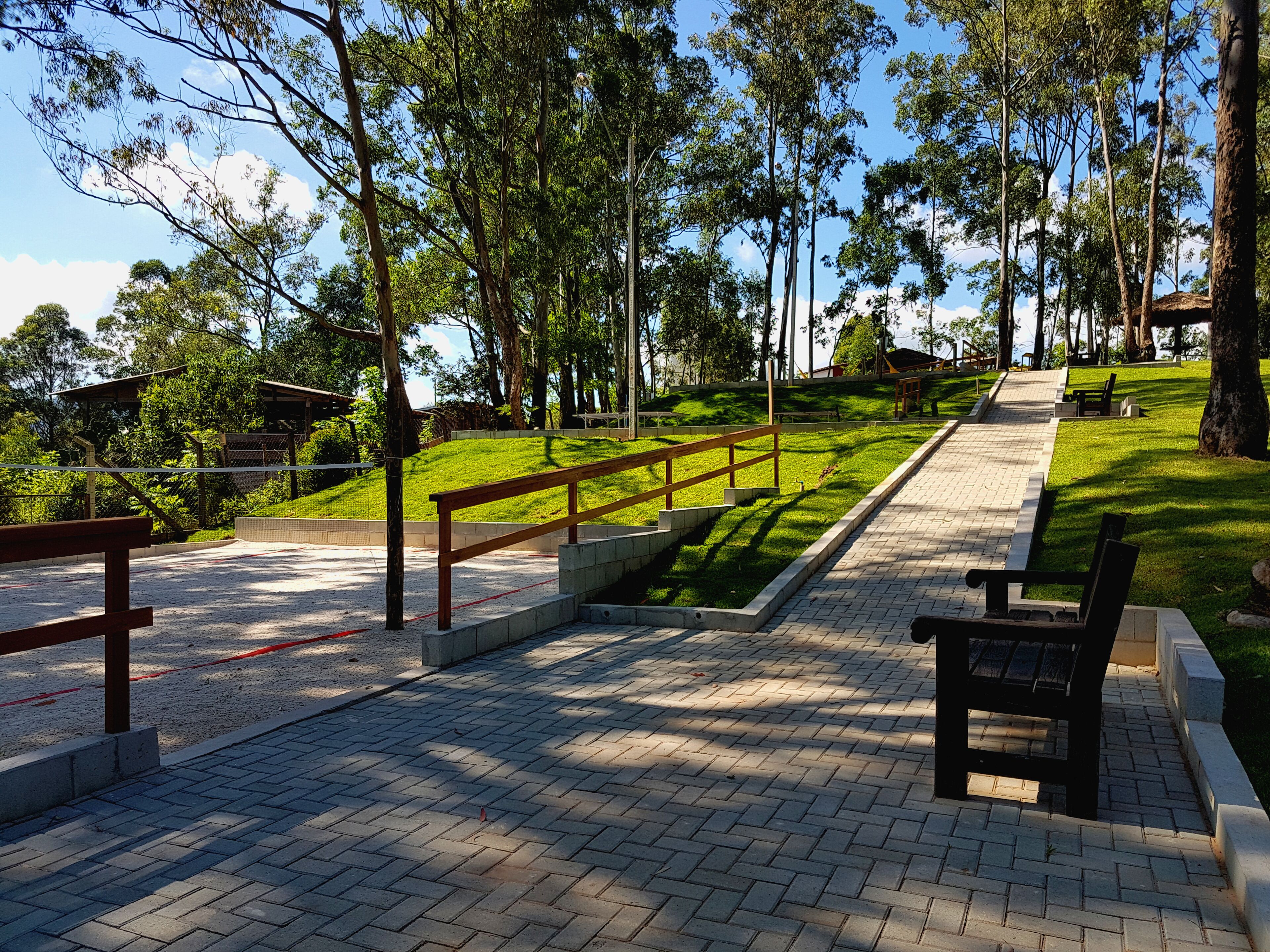 A paved pathway with benches and a wooden fence.