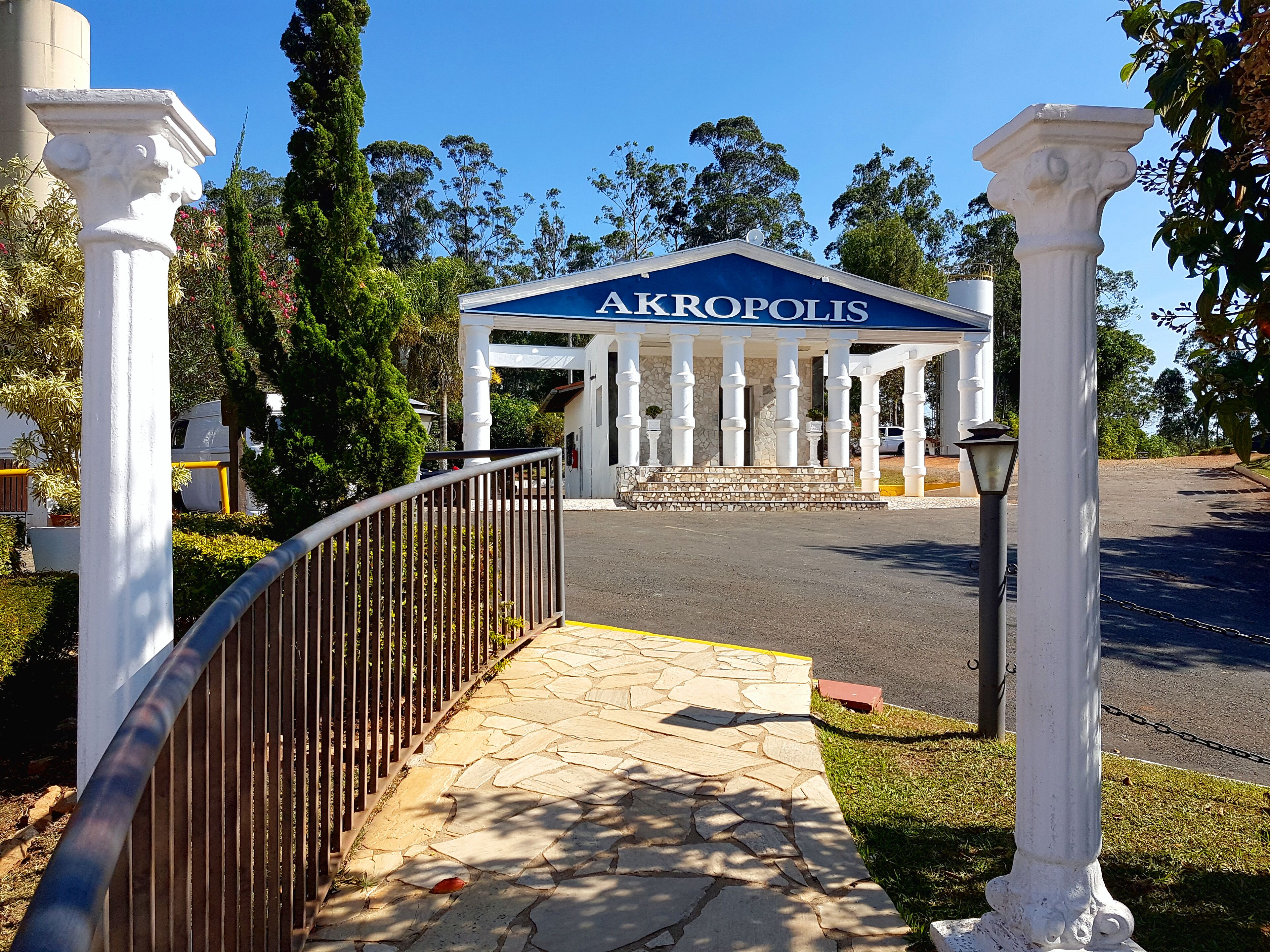 A building with a sign reading "AKROPOLIS" and a stone pathway leading to it.