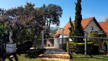 Un sendero lleva a un edificio con techo de tejas, rodeado de follaje y una estatua.
