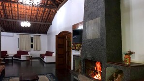 Una sala de estar acogedora con chimenea de piedra, sofás rojos y techo de madera.
