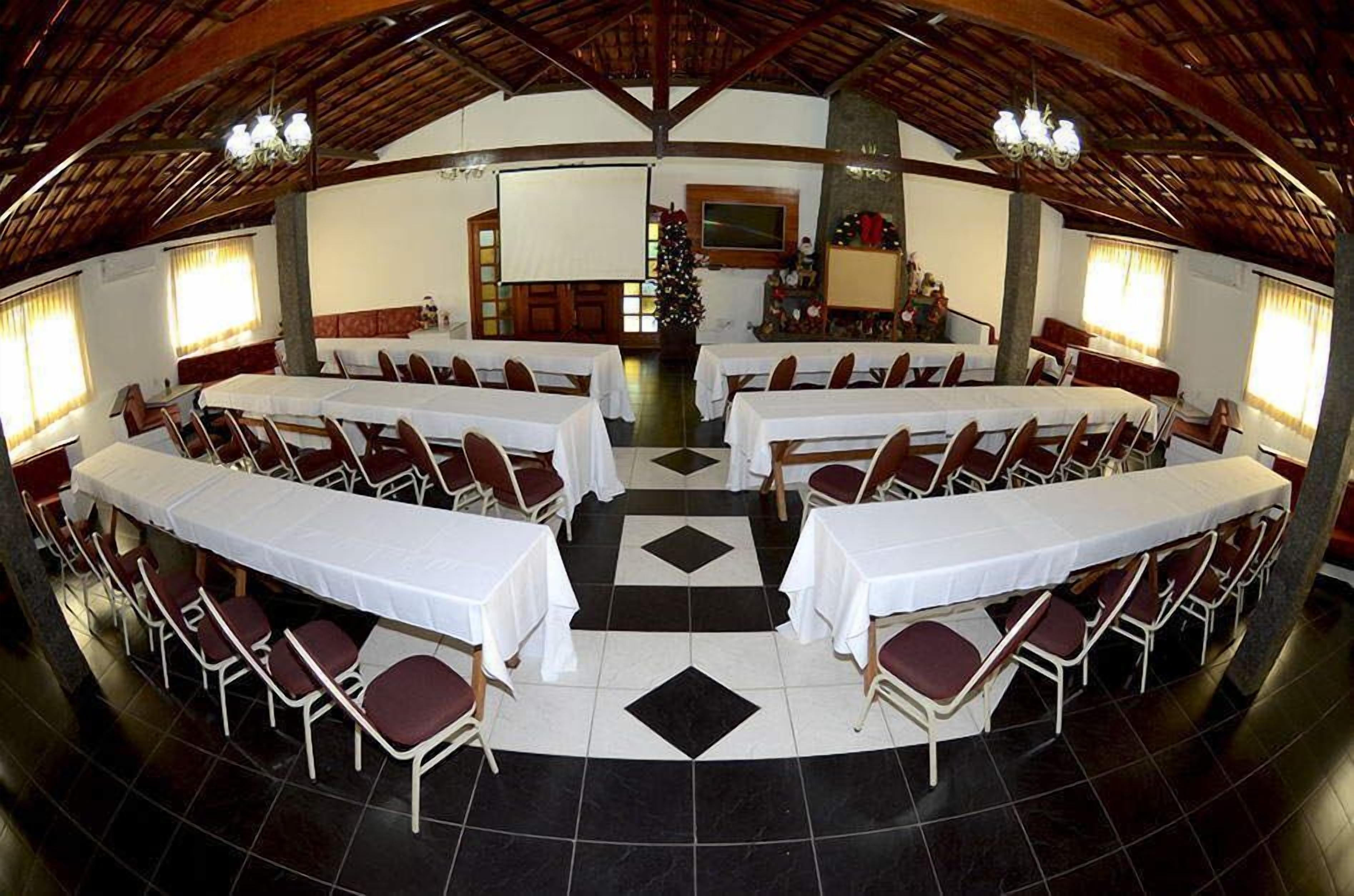 A large hall with multiple tables and chairs, a Christmas tree, and a fireplace.