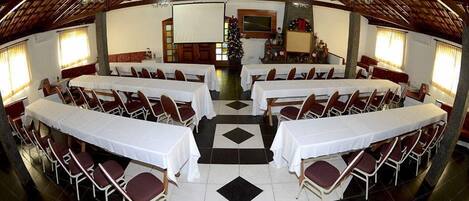 Un salón amplio con varias mesas y sillas, un árbol de Navidad y una chimenea.