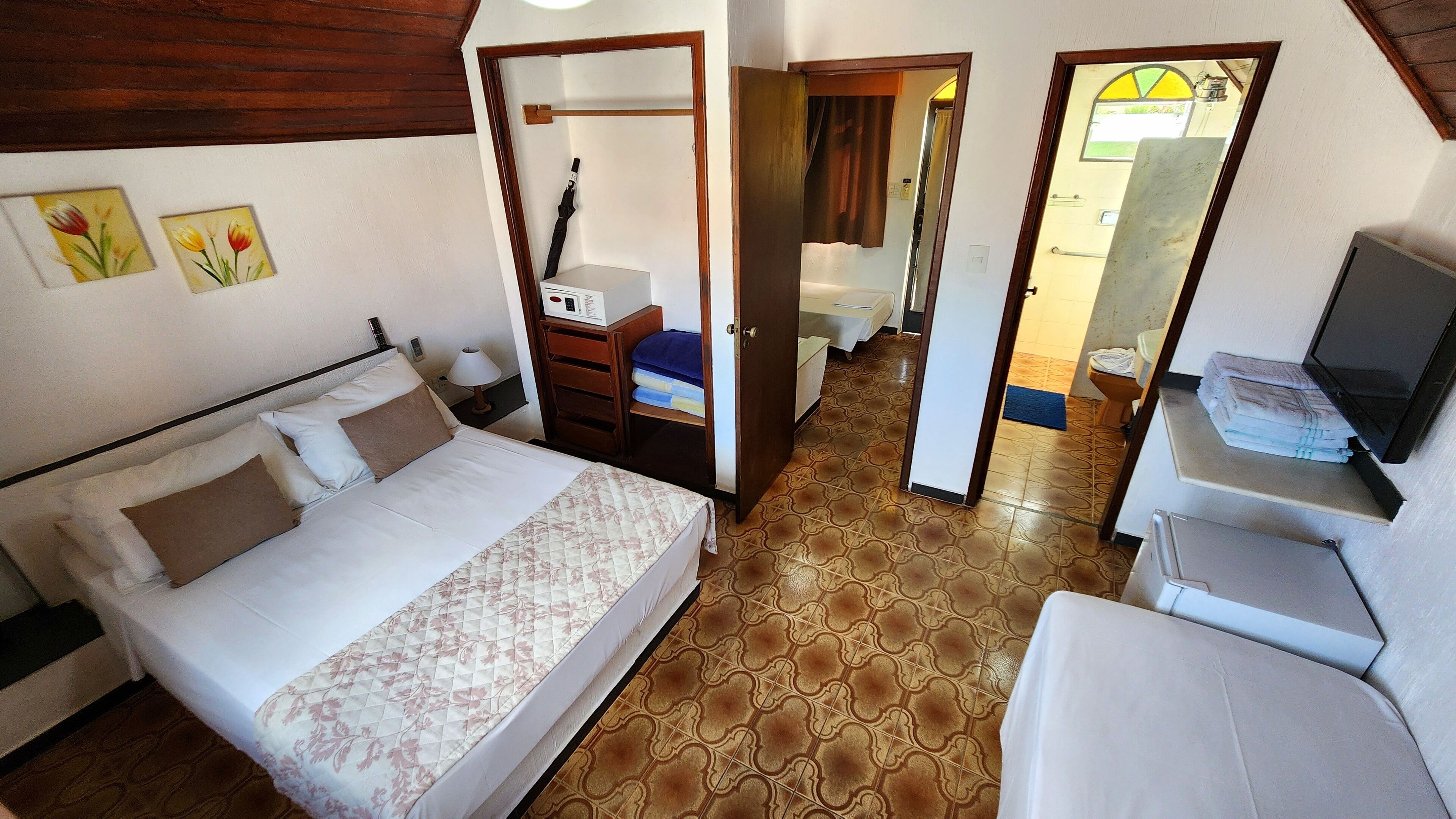 Un dormitorio con cama, escritorio y televisor.