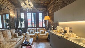 A spacious living room with a sofa, armchairs, and a coffee table. There is a kitchen area with a sink and a countertop. - Ai Cherubini (Venice)