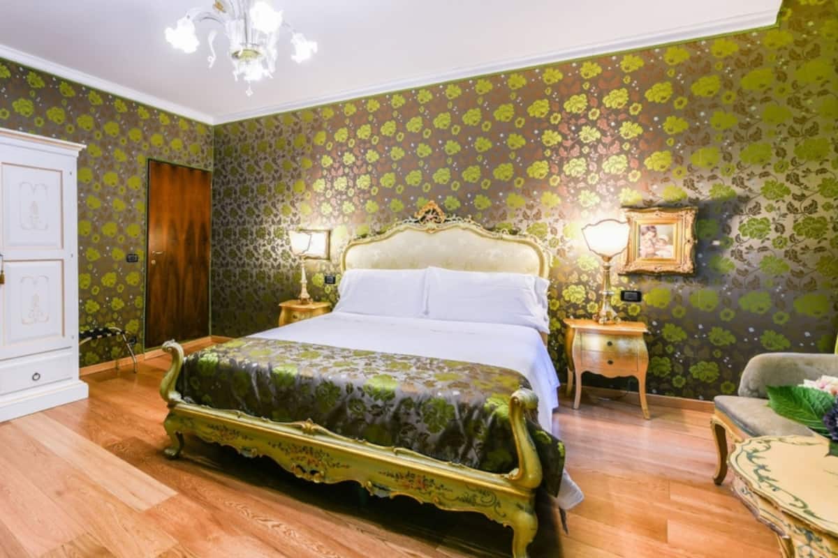 Un dormitorio con una cama grande, dos mesitas de noche con lámparas, un armario de madera y una pared con estampado verde.