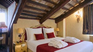 A hotel room with a large bed, two bedside tables, a lamp, and a wall-mounted light fixture. - Ai Cherubini (Venice)