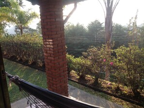 A hammock tied to a brick pillar, a grassy area, and a variety of shrubs and trees. - Chalés Pousada Serra Negra (Serra Negra)