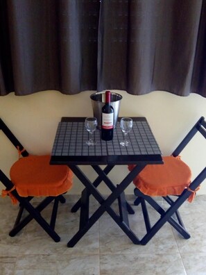 A dining table with two chairs, a wine bottle, and two glasses. - Chalés Pousada Serra Negra (Serra Negra)