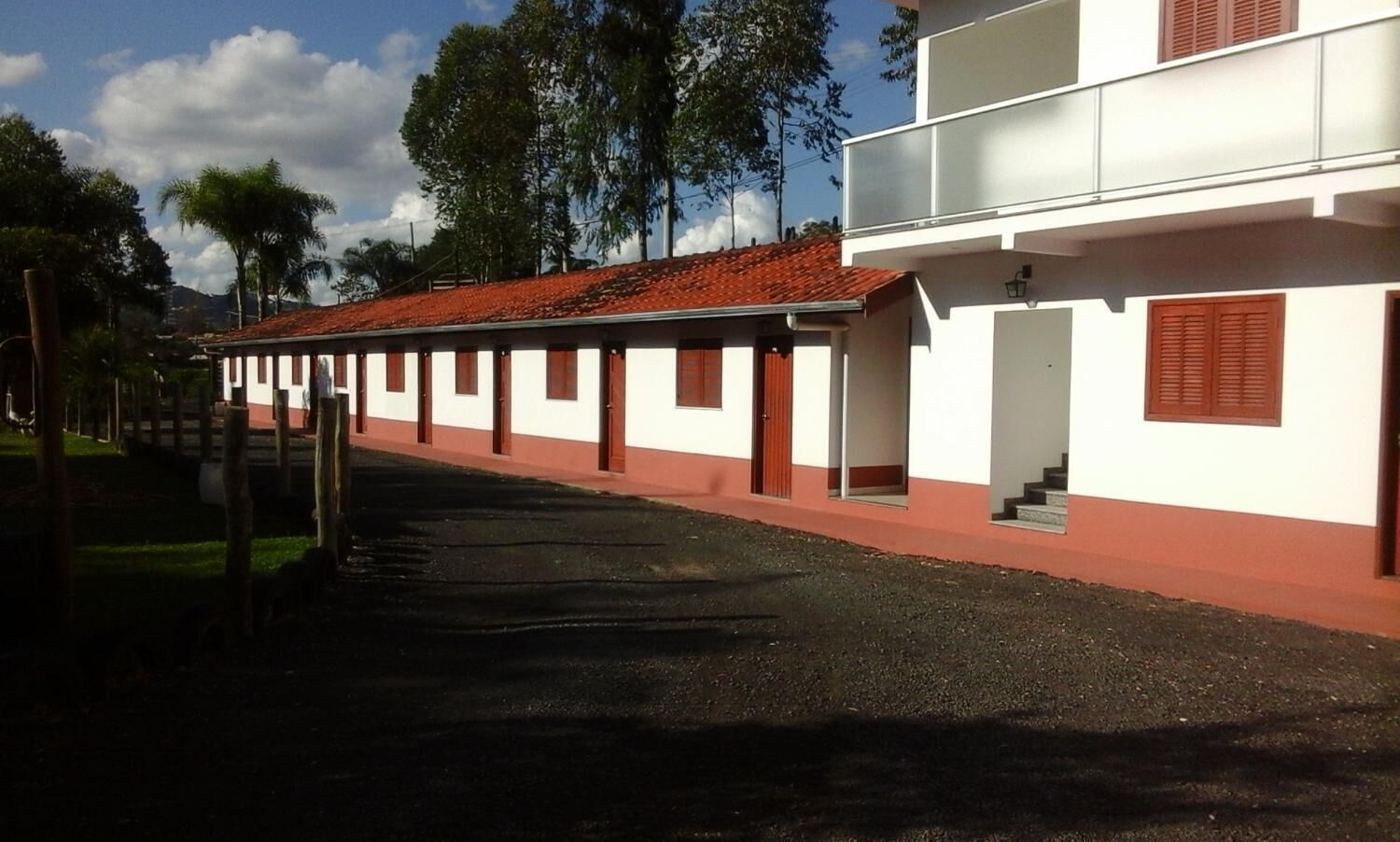 A row of white buildings with red roofs and a gravel driveway.