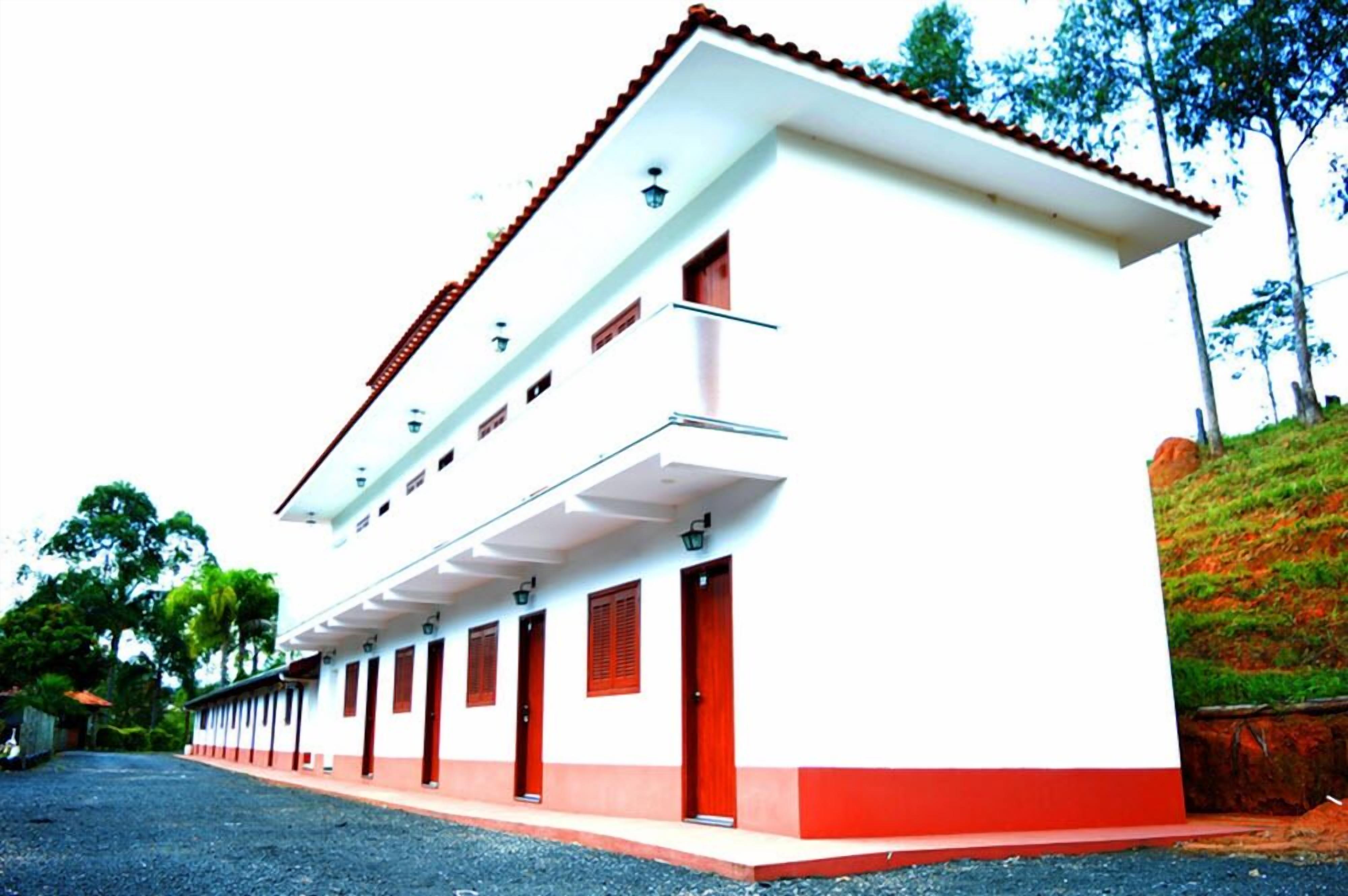 A building with a white facade, red doors, and a tiled roof.