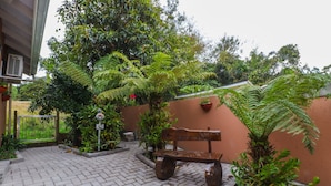 A paved courtyard with a wooden bench, potted plants, and a signpost. - Pousada Tia Eni (Gramado)