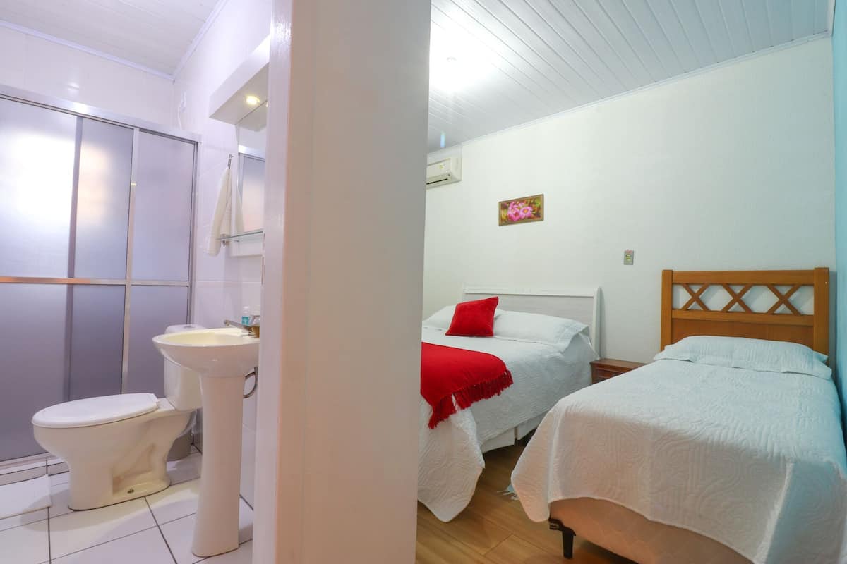 Une chambre d’hôtel équipée d’une douche, de toilettes, de deux lits et d’une petite table de chevet.
