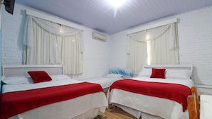 A room with two beds, each with white bedding and red pillows, and white curtains. - Pousada Tia Eni (Gramado)