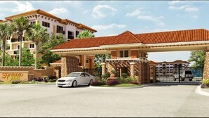 Un hotel con entrada cubierta, palmeras y un coche estacionado en la parte delantera.