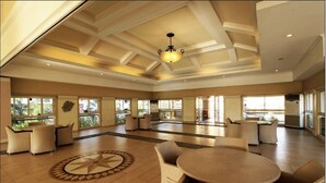 Un hall espacioso con una mesa redonda central y sillas, un diseño decorativo de estrellas en el suelo, y amplios ventanales que aportan luz natural.