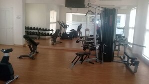 Un gimnasio con diversos equipos de ejercicio, como cintas de correr, mancuernas y máquinas de pesas.
