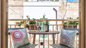 A balcony with two wooden chairs, a small table, and two decorative pillows. - Respiro del Mare (Polignano a Mare)