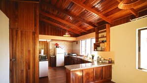 A kitchen with wooden cabinets, a central island, and a wooden ceiling. - Maris B&B (Monteverde)
