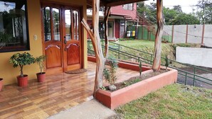A wooden entrance with a tiled porch, potted plants, and a staircase leading to a green-roofed building. - Maris B&B (Monteverde)