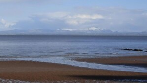 A beach with a calm sea and distant mountains. - Powillimount Cottage (Dumfries)