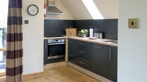 Eine Küche im modernen Design mit dunklen Schränken, einem eingebauten Ofen und einer Arbeitsplatte mit verschiedenen Geräten und Gegenständen.