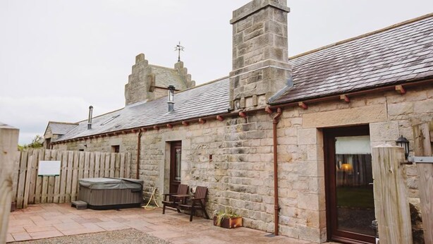 A stone building with a wooden deck, outdoor seating, and a hot tub. - Oak Cottage (Hot Tub) (Brampton)