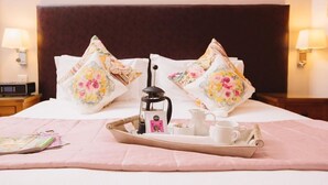 A neatly made bed with floral pillows, a tray with a coffee pot, cups, and a book. - Oak Cottage (Hot Tub) (Brampton)