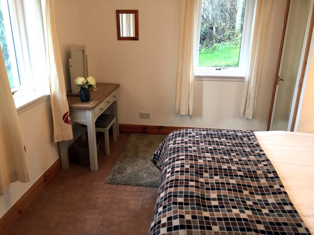 Ein Schlafzimmer mit einem Bett, einem Schreibtisch und einem Fenster mit Vorhängen.