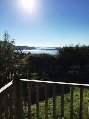 A wooden deck with a view of a lake and mountains. - Windyhill Lodge 14665 (Ullapool)