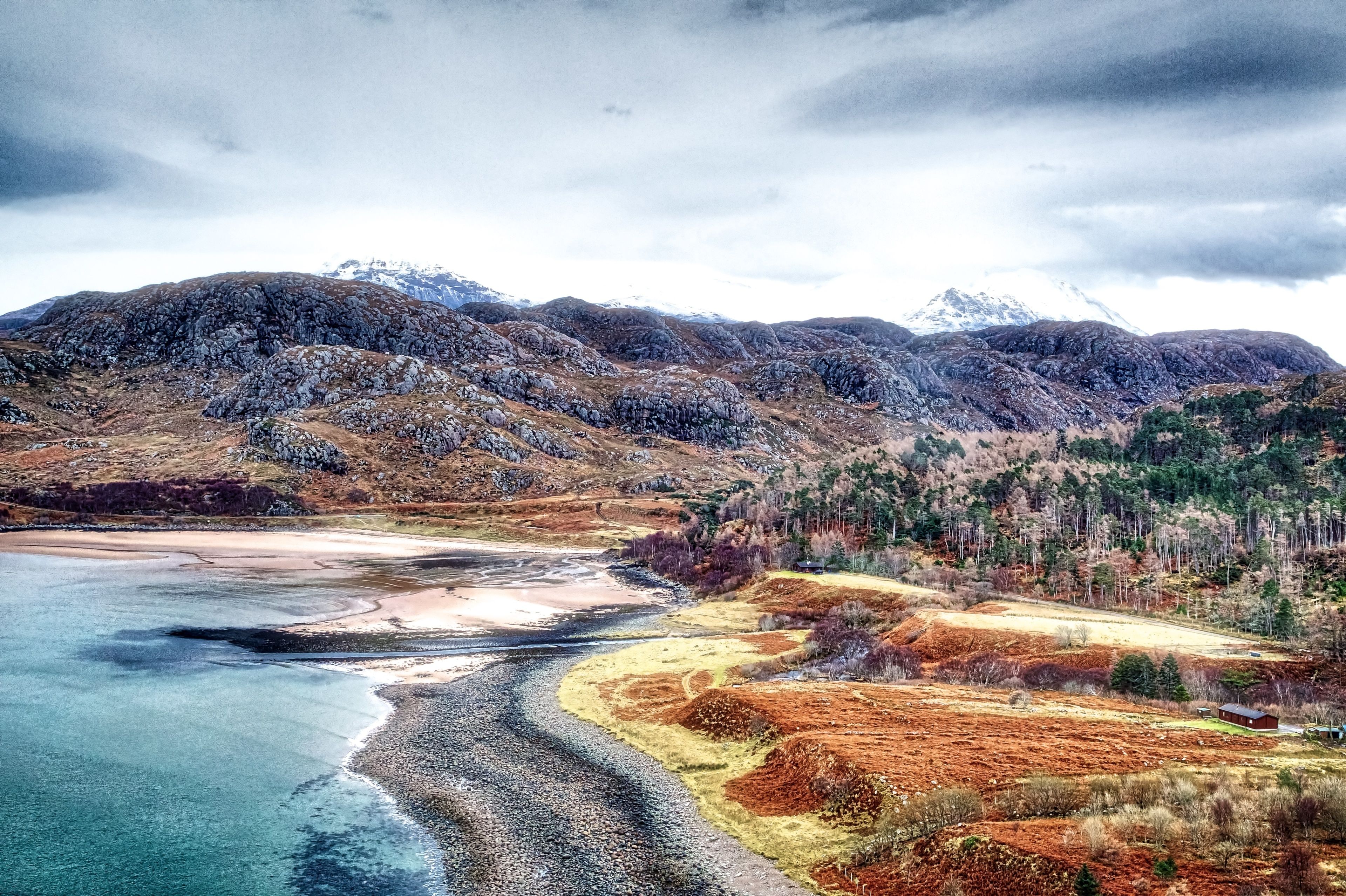 A coastal landscape with mountains, a beach, and a river.