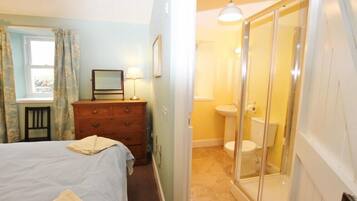 A bedroom with a bed, a dresser, a mirror, and a window with curtains.