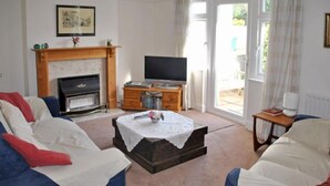 A living room with a fireplace, a television, and a sofa. - Surima, Chichester 48663 (Chichester)