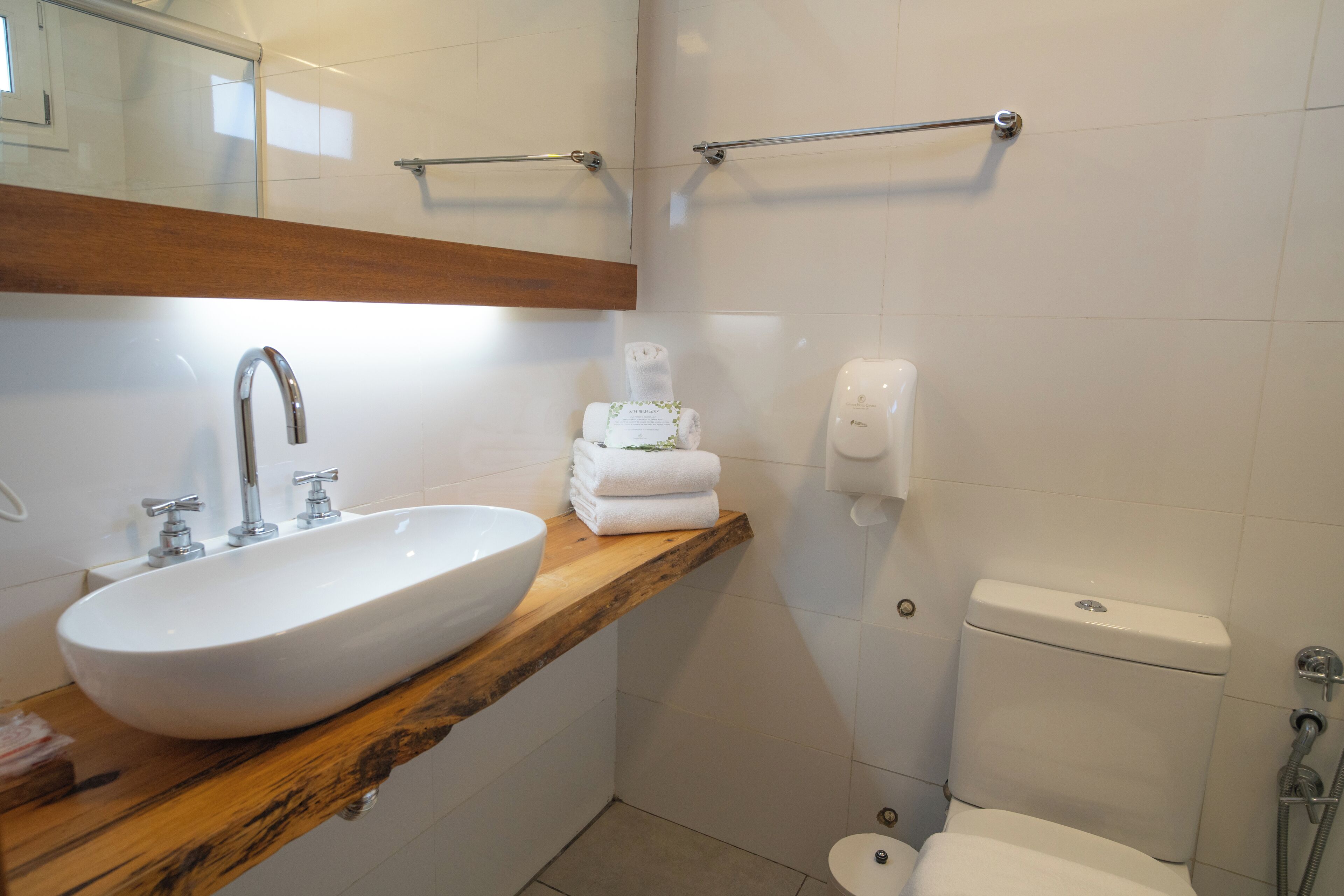 A bathroom with a white sink, wooden countertop, and a toilet.
