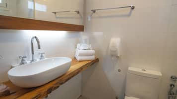 A bathroom with a white sink, wooden countertop, and a toilet.